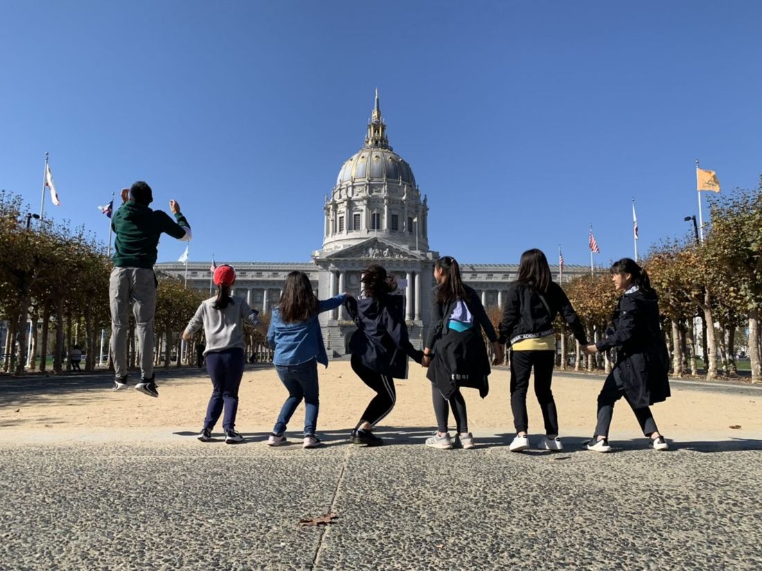 Friends jumping in front of San Francisco City Hall